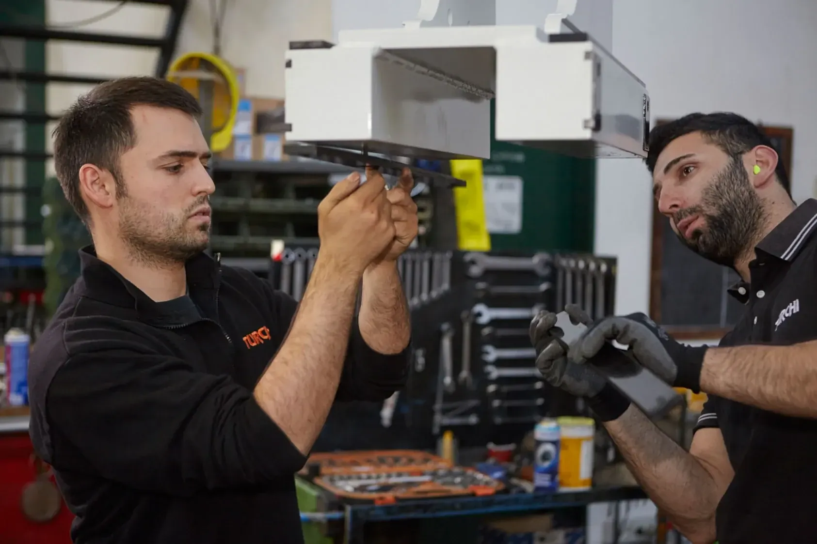 Two TURCHI technicians at the bench assembling a pile driver component